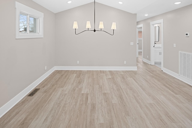 unfurnished dining area featuring vaulted ceiling and light hardwood / wood-style flooring