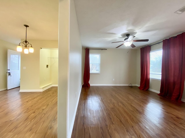 spare room with hardwood / wood-style flooring and ceiling fan with notable chandelier