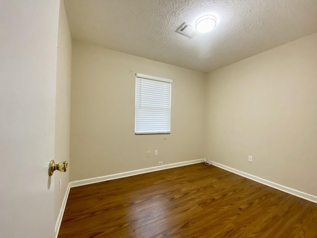 unfurnished room featuring a textured ceiling and dark hardwood / wood-style flooring