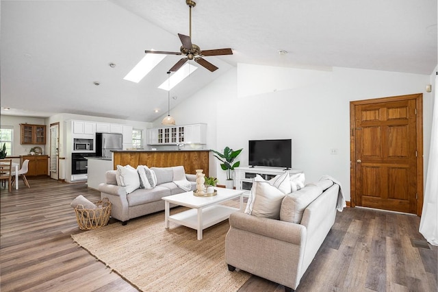 living room featuring ceiling fan, dark hardwood / wood-style floors, and lofted ceiling with skylight