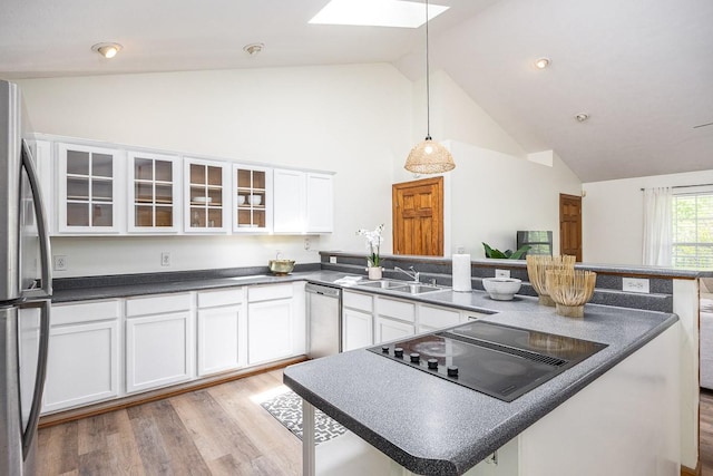 kitchen featuring white cabinetry, appliances with stainless steel finishes, lofted ceiling with skylight, and sink