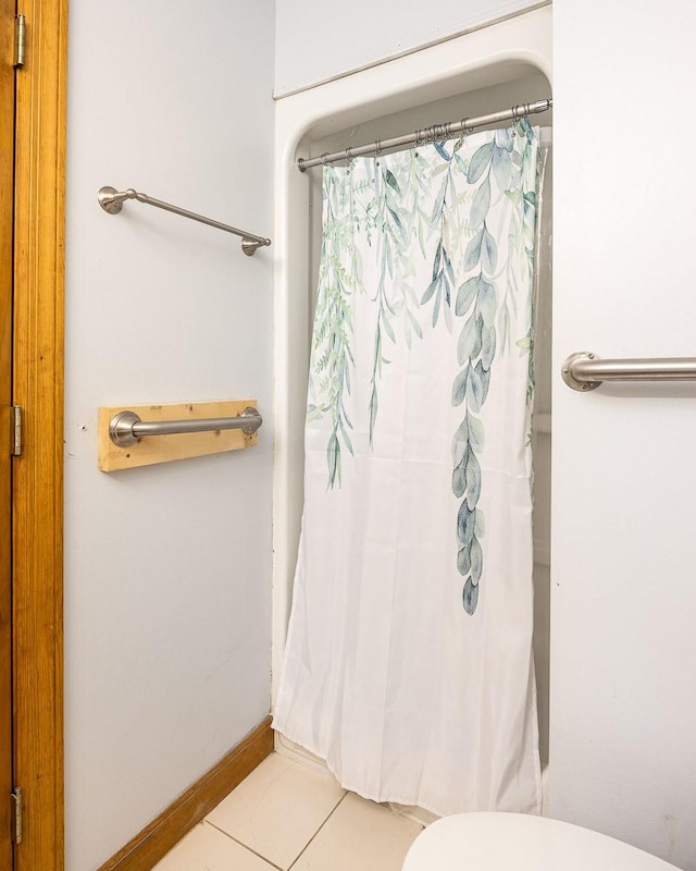 bathroom featuring curtained shower, tile patterned floors, and toilet