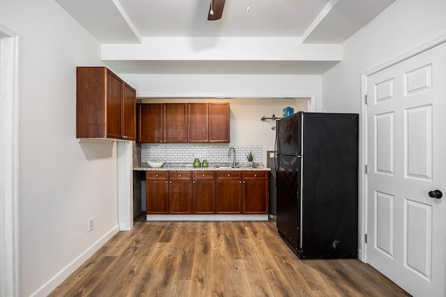 kitchen with black refrigerator, sink, backsplash, ceiling fan, and dark wood-type flooring