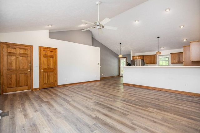 unfurnished living room with ceiling fan, high vaulted ceiling, and light wood-type flooring