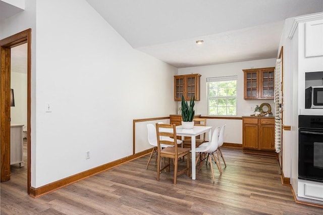 dining space with vaulted ceiling and dark hardwood / wood-style flooring