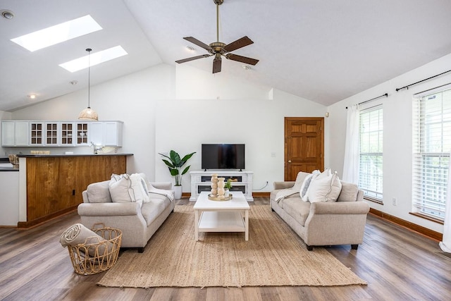 living room featuring wood-type flooring, lofted ceiling with skylight, and ceiling fan