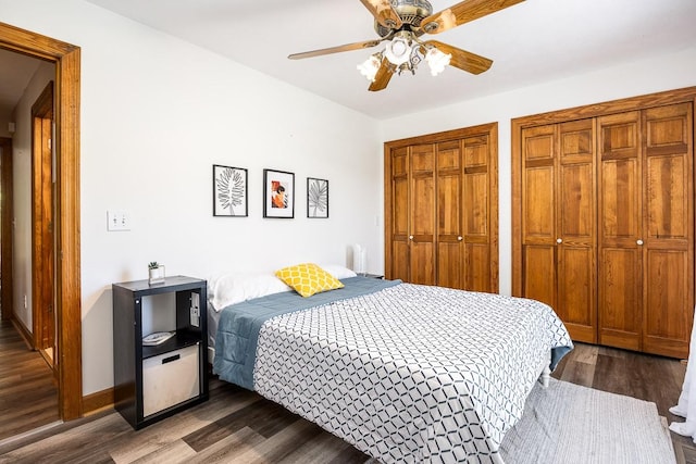 bedroom with multiple closets, ceiling fan, and dark hardwood / wood-style flooring