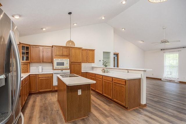 kitchen featuring dark wood-type flooring, built in microwave, hanging light fixtures, stainless steel refrigerator, and a kitchen island