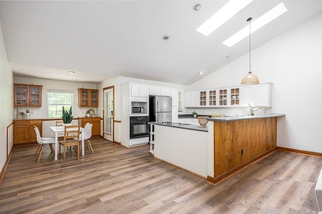 kitchen with white cabinetry, a skylight, kitchen peninsula, pendant lighting, and stainless steel appliances