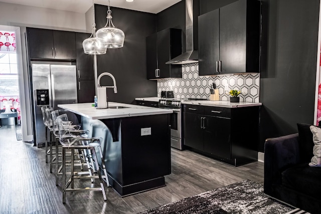 kitchen featuring sink, hanging light fixtures, a center island with sink, appliances with stainless steel finishes, and a kitchen breakfast bar