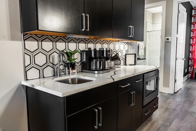 kitchen featuring built in microwave, sink, light stone counters, dark hardwood / wood-style floors, and decorative backsplash