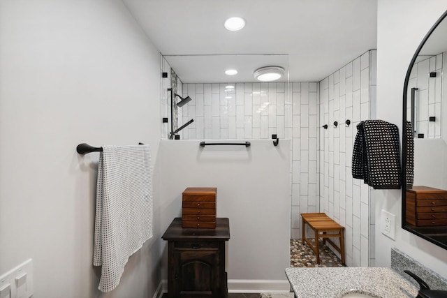 bathroom with tiled shower and vanity