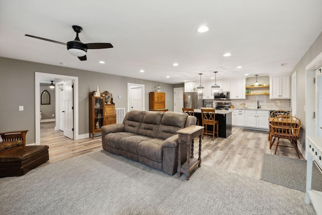 living room featuring sink, ceiling fan, and light wood-type flooring