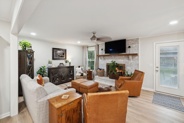 living room with light hardwood / wood-style flooring, crown molding, a fireplace, and ceiling fan