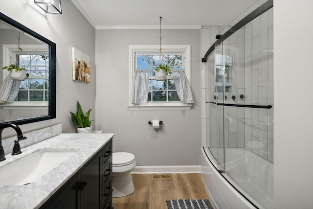 full bathroom featuring toilet, wood-type flooring, vanity, ornamental molding, and enclosed tub / shower combo