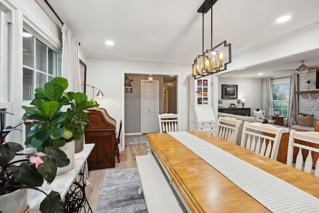 dining area featuring ceiling fan, a large fireplace, and light wood-type flooring