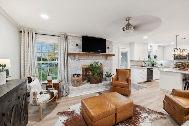 living room featuring sink, crown molding, light hardwood / wood-style flooring, and a brick fireplace