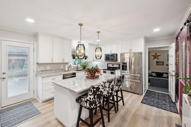 kitchen with white cabinetry, a kitchen bar, a kitchen island, and appliances with stainless steel finishes