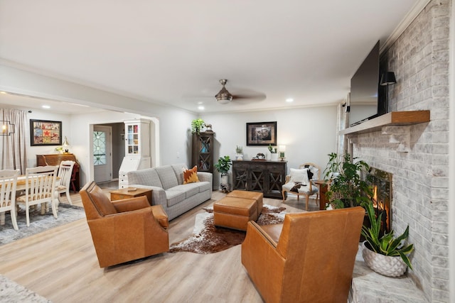 living room with a brick fireplace, light hardwood / wood-style floors, and ceiling fan