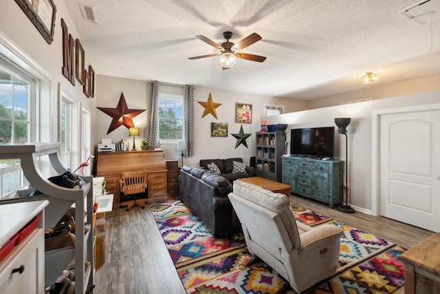 living room featuring ceiling fan, hardwood / wood-style floors, and a textured ceiling