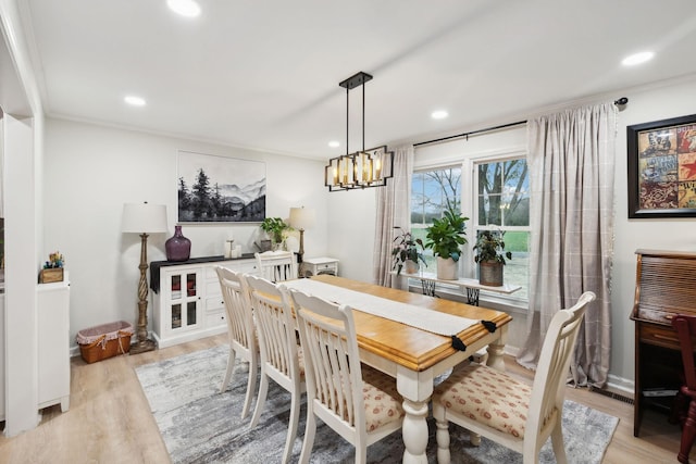 dining space featuring ornamental molding, a chandelier, and light hardwood / wood-style flooring