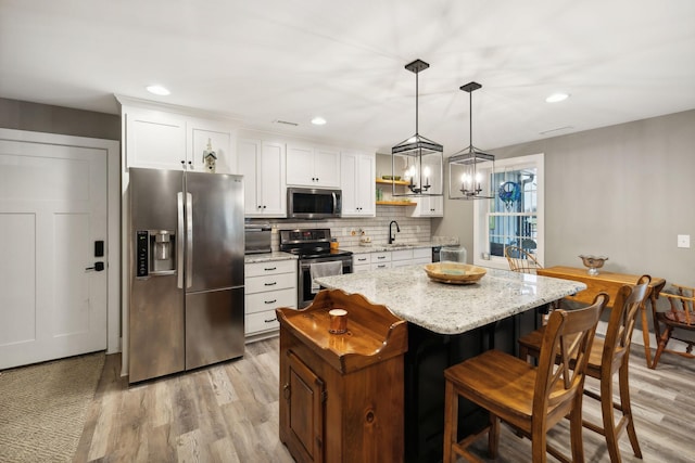 kitchen featuring pendant lighting, sink, appliances with stainless steel finishes, white cabinets, and a kitchen island