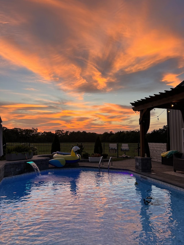 pool at dusk featuring pool water feature