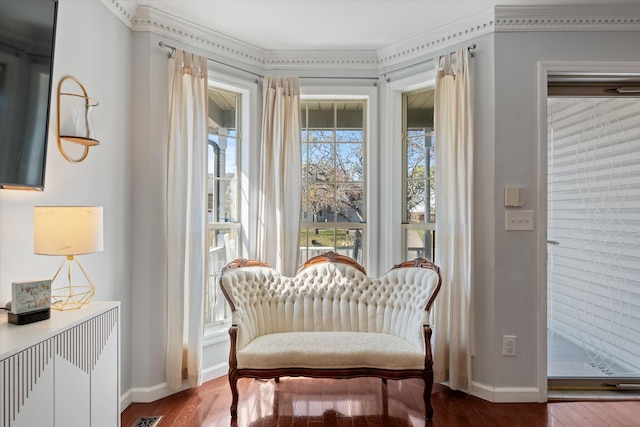 living area with wood-type flooring, a healthy amount of sunlight, and crown molding