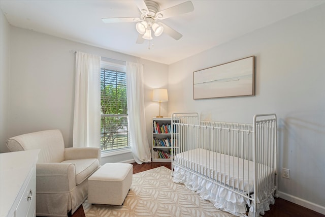 bedroom with a crib, hardwood / wood-style floors, and ceiling fan