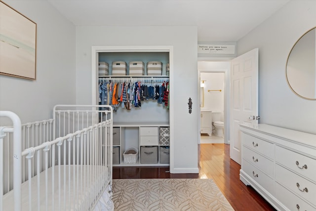 bedroom with a nursery area, hardwood / wood-style floors, and a closet