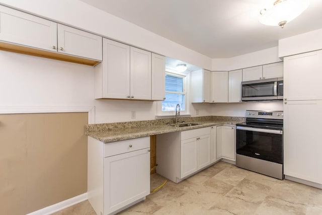 kitchen featuring white cabinetry, appliances with stainless steel finishes, sink, and light stone counters