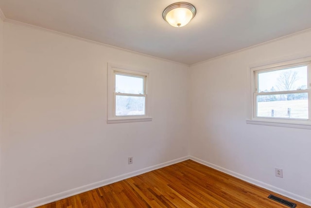 empty room with hardwood / wood-style floors and ornamental molding