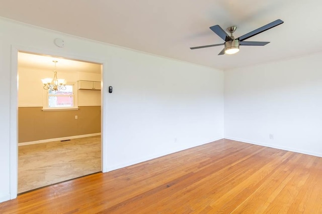 empty room featuring wood-type flooring and ceiling fan with notable chandelier