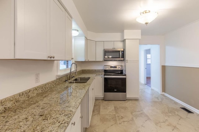 kitchen with white cabinetry, sink, stainless steel appliances, and light stone countertops