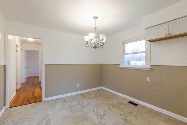 spare room featuring a notable chandelier and crown molding