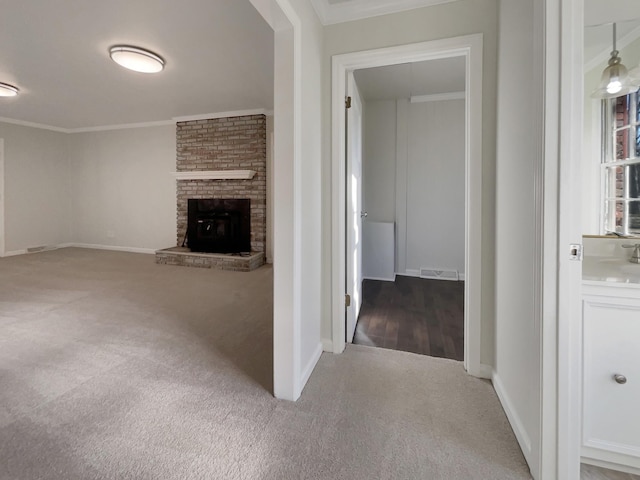 unfurnished living room with a brick fireplace, crown molding, and carpet floors