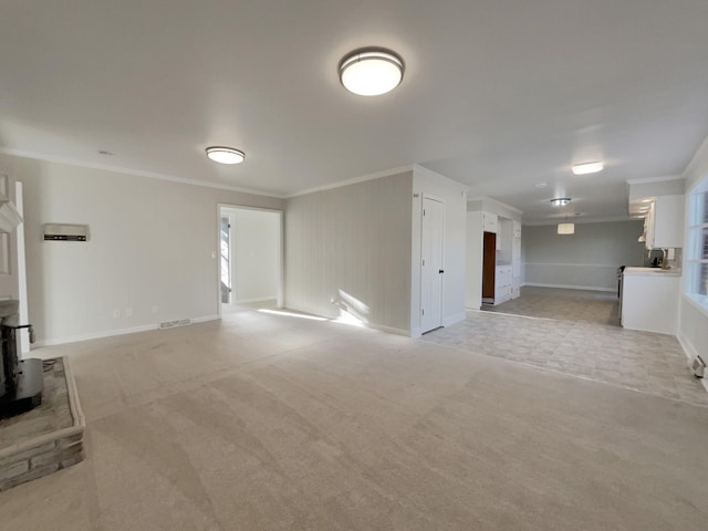 unfurnished living room with ornamental molding, light carpet, and a wood stove