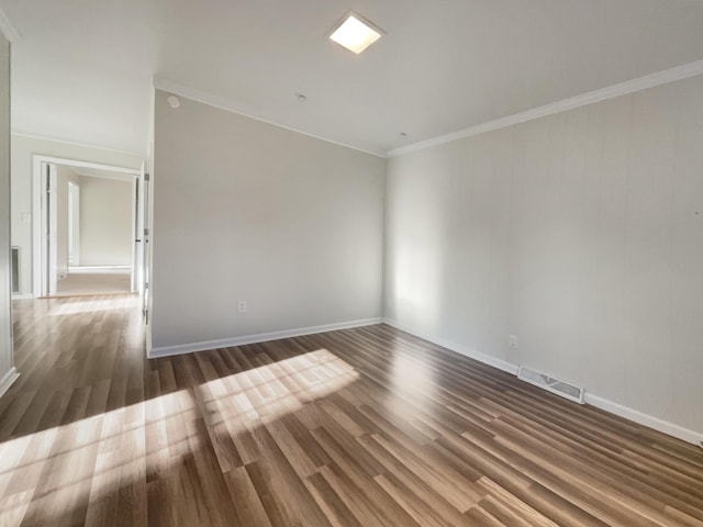 empty room featuring dark wood-type flooring and ornamental molding