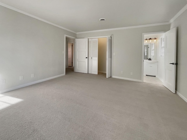 unfurnished bedroom featuring ensuite bathroom, sink, ornamental molding, and light carpet