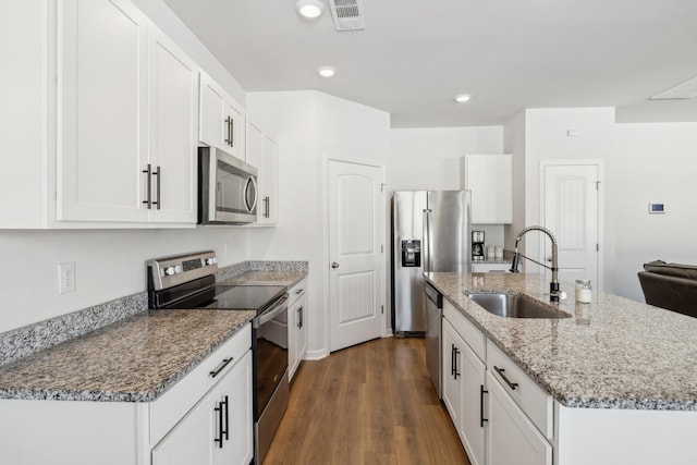 kitchen featuring sink, a center island with sink, appliances with stainless steel finishes, dark hardwood / wood-style floors, and white cabinets