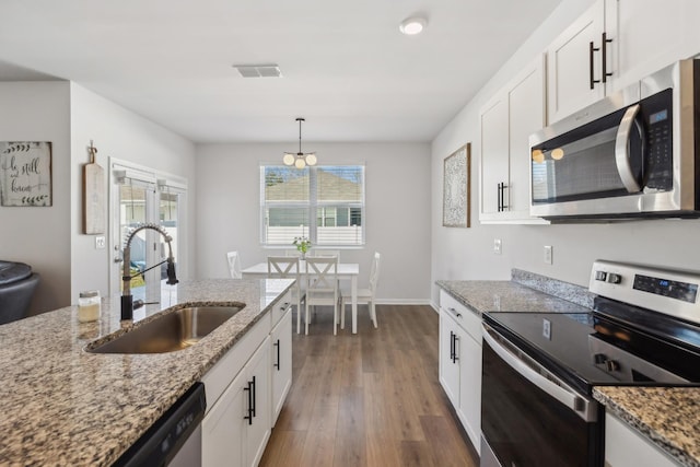 kitchen featuring sink, white cabinetry, hanging light fixtures, appliances with stainless steel finishes, and stone counters