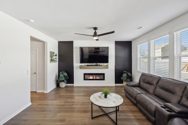 living room with dark wood-type flooring, a fireplace, and ceiling fan