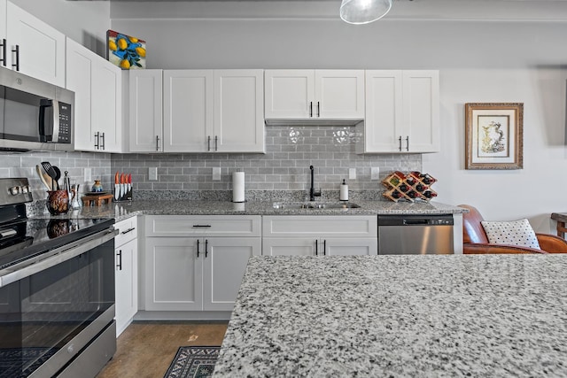 kitchen with white cabinetry, stainless steel appliances, light stone countertops, and sink