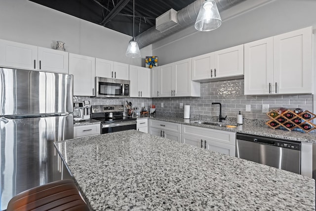 kitchen with sink, white cabinetry, appliances with stainless steel finishes, pendant lighting, and backsplash