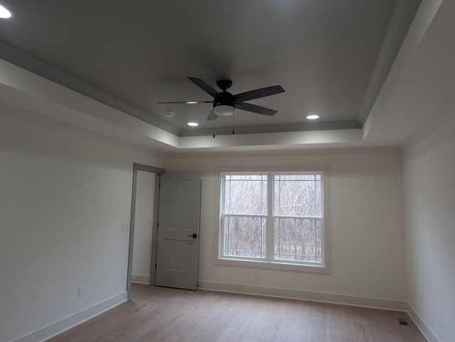 spare room with light hardwood / wood-style flooring, ornamental molding, a raised ceiling, and ceiling fan