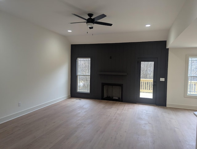 unfurnished living room with ceiling fan, a fireplace, and light hardwood / wood-style floors