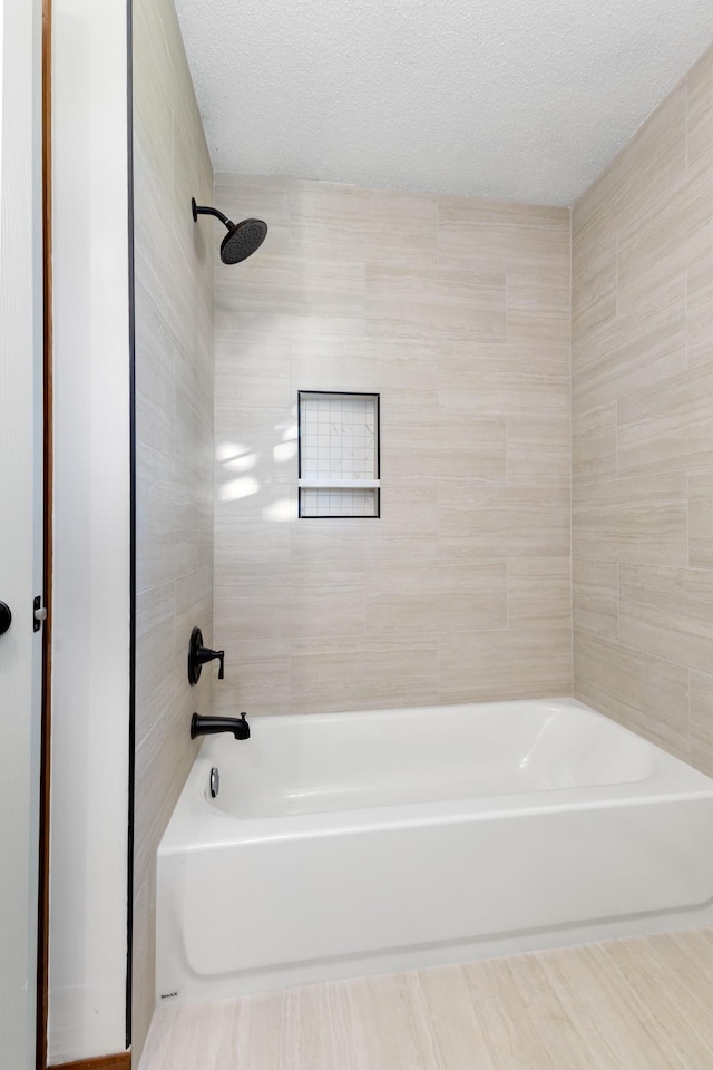 bathroom featuring tiled shower / bath combo and a textured ceiling