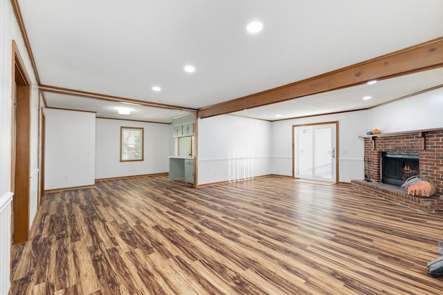 unfurnished living room with a brick fireplace, hardwood / wood-style flooring, a wealth of natural light, and ornamental molding