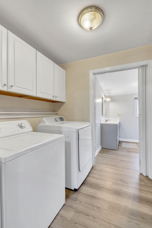 laundry room with washer and dryer, light hardwood / wood-style floors, and cabinets