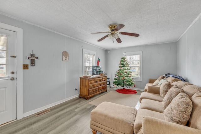 living room featuring crown molding, ceiling fan, and light wood-type flooring